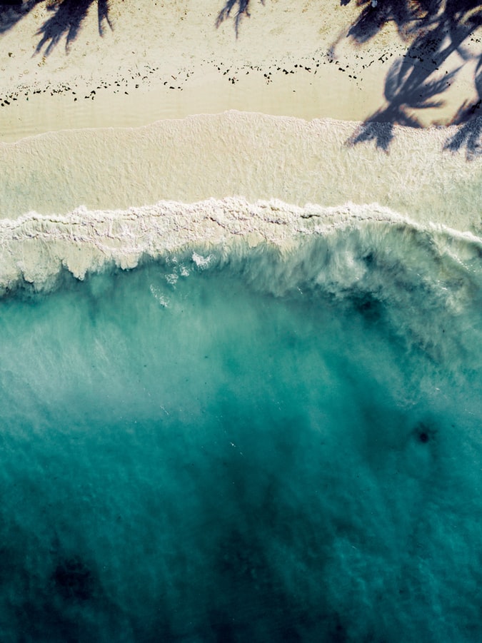 Photo aérienne de l'eau turquoise longeant la plage de Zanzibar